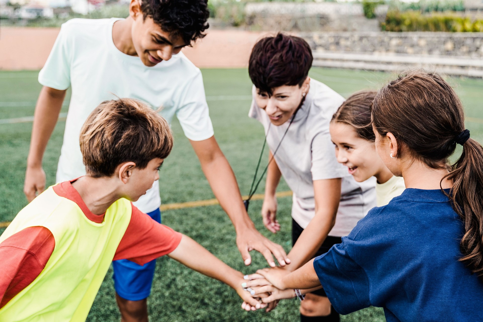 Happy group of kid soccer players stacking hands having fun together outdoor - Atheltic child sport concept