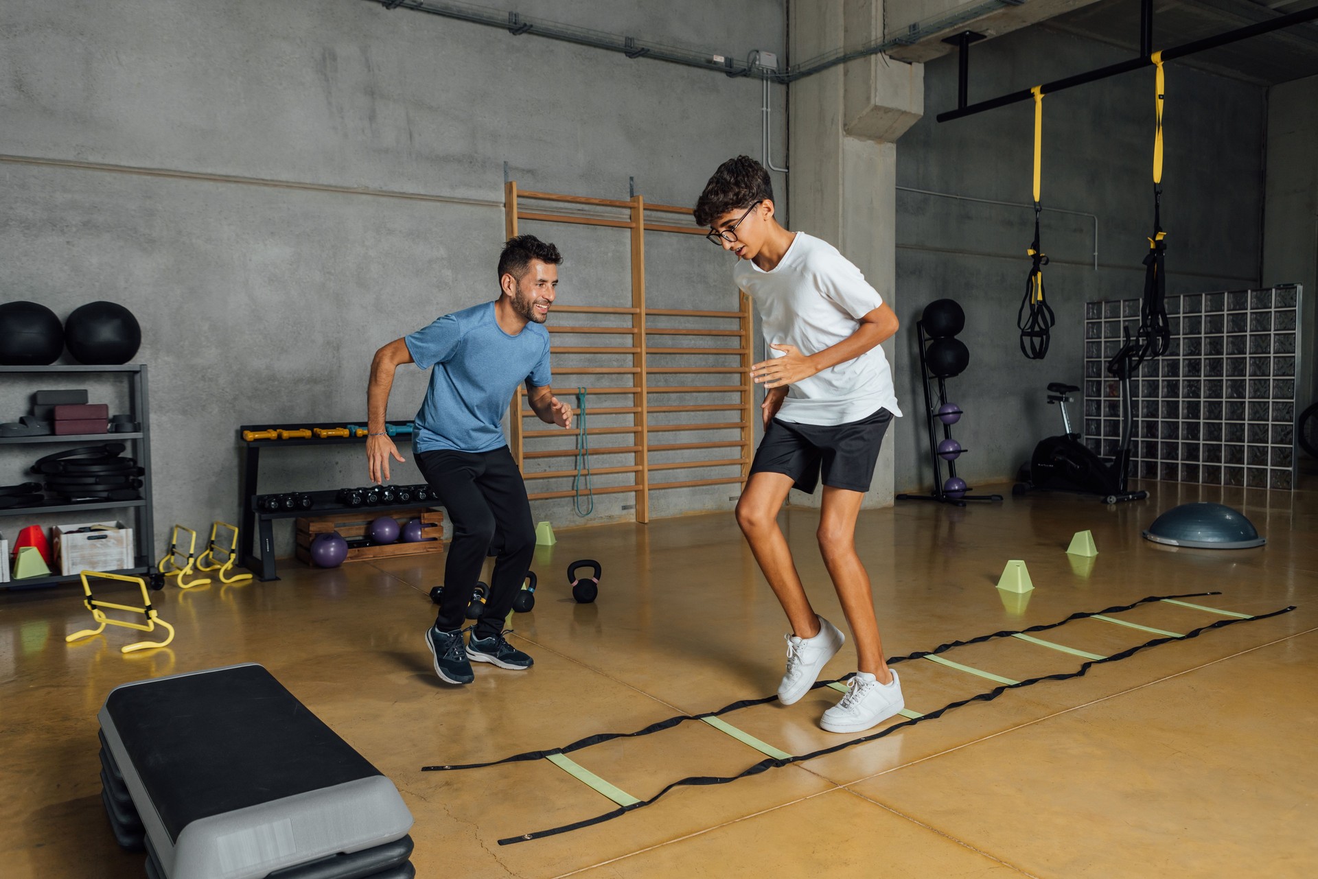 Personal trainer encouraging boy during circuit training routine at gym