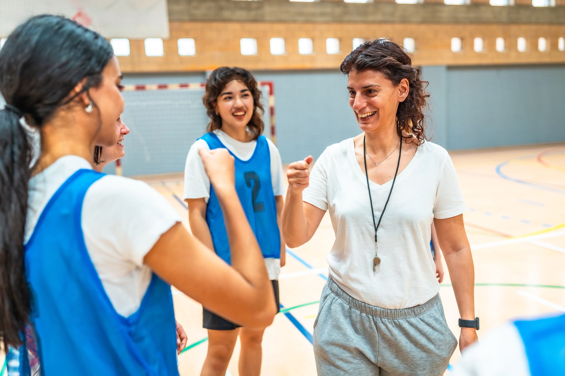 Female basketball coach motivating players in gym